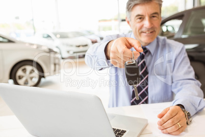 Smiling salesman holding a customer car key