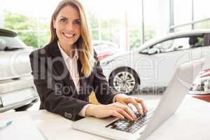 Smiling saleswoman typing on her laptop