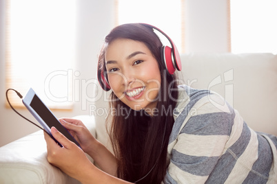 Smiling asian woman on couch listening to music