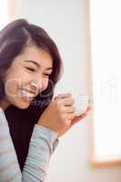 Asian woman relaxing on couch with coffee