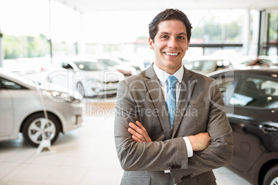 Smiling salesman standing with arms crossed