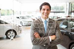 Smiling salesman standing with arms crossed