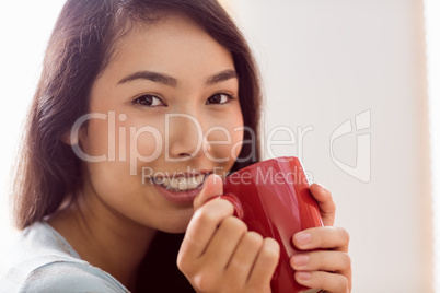 Asian woman relaxing on couch with coffee