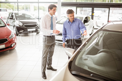 A man showing a car to the salesman A man showing a car to the salesman