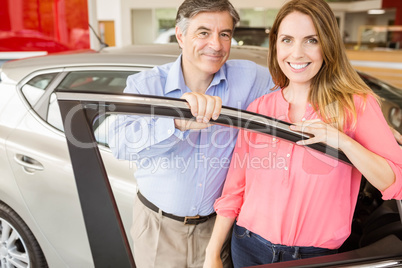 Smiling couple leaning on car