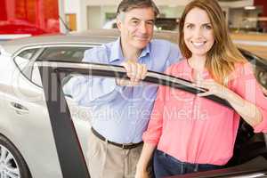 Smiling couple leaning on car