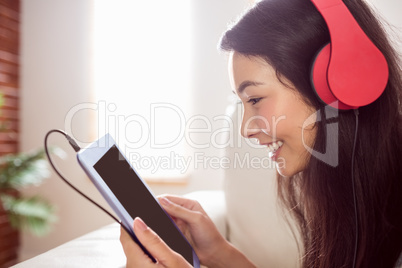 Smiling asian woman on couch listening to music