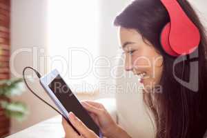 Smiling asian woman on couch listening to music