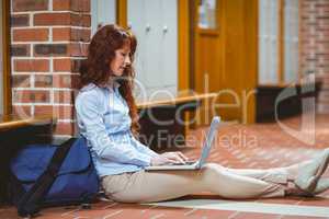 Mature student using laptop in hallway