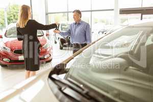Saleswoman giving car keys while shaking hand of a client