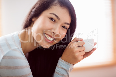 Asian woman relaxing on couch with coffee