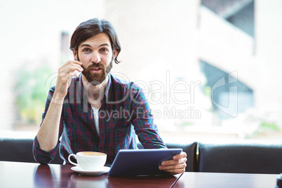 Hipster student using tablet in canteen