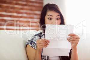 Asian woman on the couch reading letter
