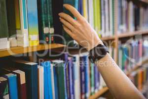 Student picking book in library wearing smart watch