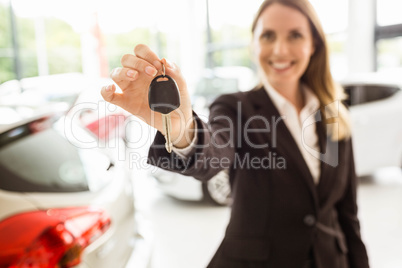 Smiling saleswoman holding car key
