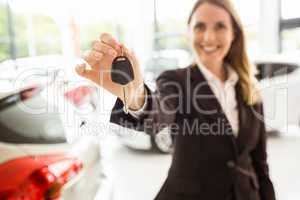 Smiling saleswoman holding car key