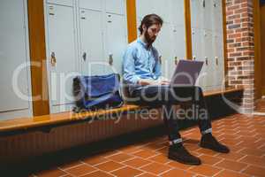 Hipster student using laptop in hallway