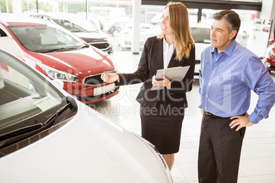 Smiling businesswoman showing car to customer