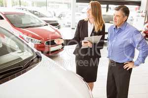 Smiling businesswoman showing car to customer