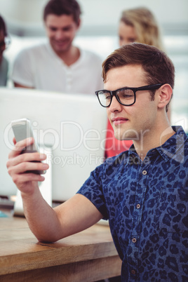 Smiling creative businessman working near co workers