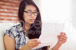 Asian woman on the couch reading letter