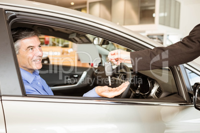 Salesman giving keys to a smiling businessman