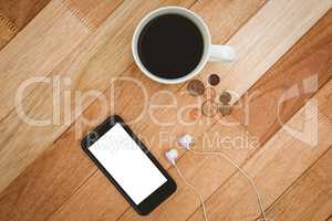 Coffee and black smartphone with white headphones