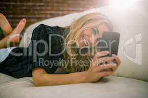 Pretty blonde relaxing on the couch using phone