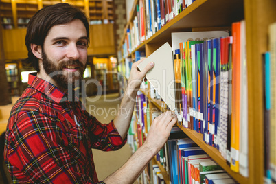 Happy student picking book in library