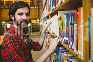 Happy student picking book in library