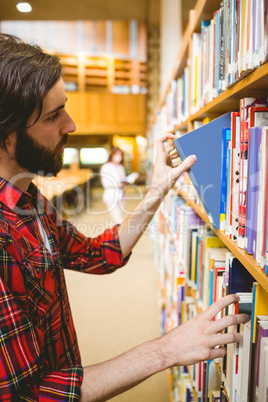 Hipster student picking a book in library