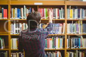 Student picking a book from shelf in library