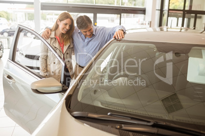 Smiling couple leaning on car