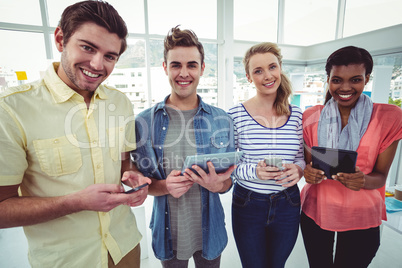 Smiling creative team standing in a line using technology