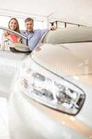 Smiling couple leaning on car