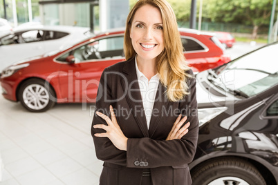 Smiling saleswoman standing with arms crossed