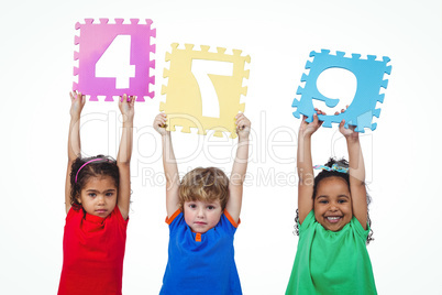 Three kids holding number shanpes above their heads