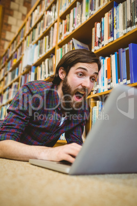 Student using laptop on floor in the library Student using laptop on floor in the library
