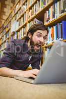 Student using laptop on floor in the library