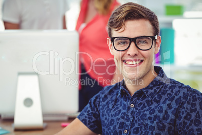 Smiling creative businessman working near co workers