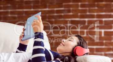 Asian woman lying on the couch listening to music