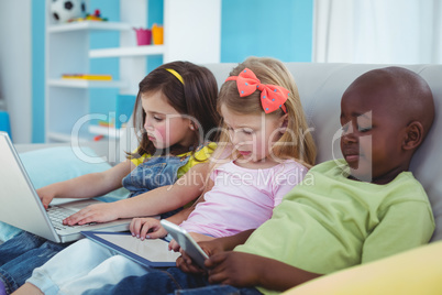 Happy kids sitting together with a tablet and laptop and phone