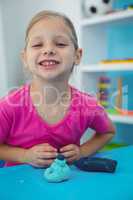 Smiling girl playing with modelling clay