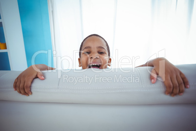 Happy kid looking from the back of the couch