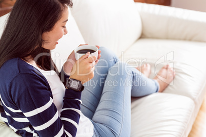 Asian woman relaxing on couch with coffee