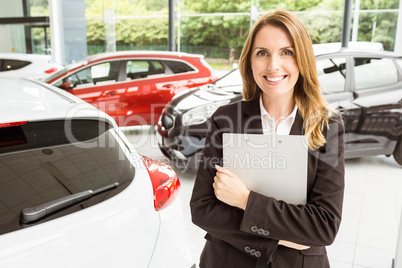 Smiling saleswoman holding document while looking at camera