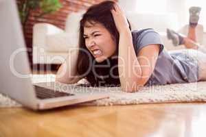 Asian angry woman using laptop on floor