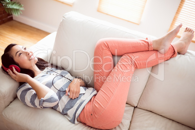 Smiling asian woman on couch listening to music