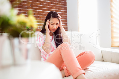 Asian woman getting headache on couch