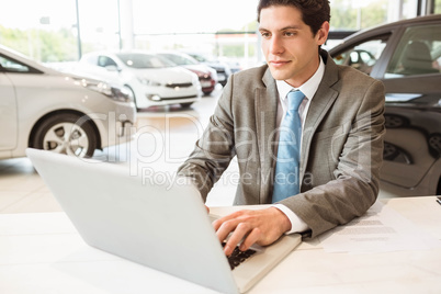 Smiling salesman writing on his laptop